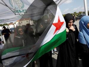 نساء يحملن علم الجيش السوري الحر في تجمع قبل مغادرة قافلة مساعدات تركية اسطنبول متوجهة إلى إدلب السورية
