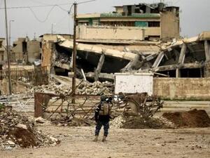 أحد أفراد قوات الشرطة الاتحادية العراقية يقف بالقرب من مبان مدمرة جراء اشتباكات مع مقاتلي تنظيم الدولة الإسلامية في الموصل

