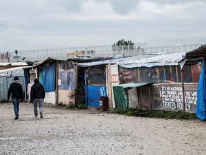 People walk in the main street of the ''Jungle'' migrant camp where all makeshift shops have closed as French Interior Minister said on the eve the demolition of the camp would take place "within days" on October 19, 2016. (AFP/Denis Charlet)