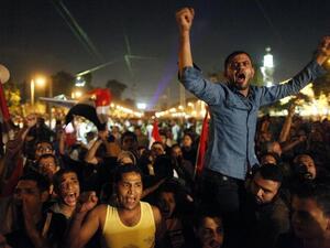 Egyptian protesters calling for the ouster of President Mohamed Morsi react as they watch his speech on a big screen (Mahmud Khaled / AFP)