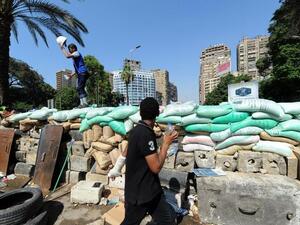 EGYPT, Cairo : A supporter of the Muslim Brotherhood and Egypt's ousted president Mohamed Morsi stands on top of a make-shift barricade as they demonstrate near Cairo university on July 26, 2013. (AFP PHOTO/FAYEZ NURELDINE) 