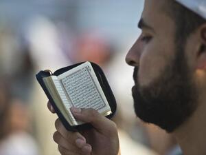 EGYPT, Cairo : A supporter of Egypt's deposed president Mohamed Morsi reads the Koran during a rally calling for his release and re-instatement outside Rabaa al-Adawiya mosque in Cairo on August 4, 2013. AFP PHOTO / KHALED DESOUKI