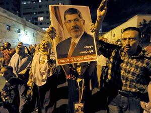 EGYPT, Alexandria : Supporters of Egypt's deposed president Mohamed Morsi, hold up his image during a protest in the Mediterranean city of Alexandria late on August 5, 2013. AFP PHOTO/STR