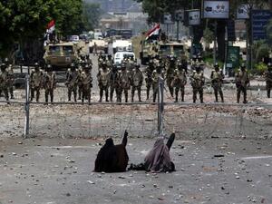 Egyptian supporters of deposed president Mohamed Morsi sit in front of barbed wire fencing that blocks the access to the headquarters of the Republican Guard in Cairo on July 8, 2013. (AFP/PHOTO / MAHMUD HAMS)