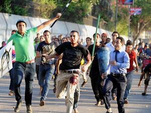 A supporter of deposed Egyptian President Mohamed Morsi is seen beaten by pro-government and army supporters during clashes. [AFP]