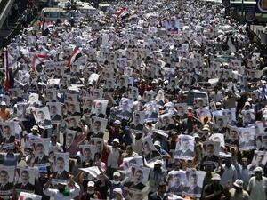 Supporters of the Muslim Brotherhood and Egypt's ousted president Mohamed Morsi carry his portrait as they demonstrate outside Rabaa al-Adawiya mosque on July 26, 2013. AFP PHOTO/MOHAMED EL-SHAHED