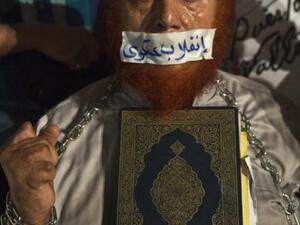 EGYPT, Cairo : An Egyptian man holds a copy of Quran and puts tape on his mouth with Arabic slogan "Military coup" during an open sit in outside Rabaa al-Adawiya mosque in Cairo on August 1, 2013. AFP PHOTO / KHALED DESOUKI