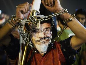 EGYPT, Cairo : A chained protester wearing a picture of President Morsi poses as hundreds of Egyptian anti-government protesters shout political slogans against Egyptian President Mohammed Morsi in Egypt's landmark Tahrir square as they watch Morsi's speech protesting against government and the Muslim Brotherhood on June 26. (AFP)