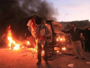 متظاهرون بجانب إحدى عربات الأمن المدمرة في ميدان التحرير 