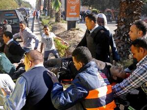 Egyptian emergency services carry a wounded victim at the site of a bomb attack next to a police checkpoint in the western Talibiya district of the capital Cairo on December 9, 2016. (AFP/Stringer)