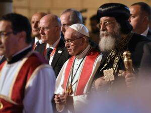 Pope Francis (C) stands near to Coptic Pope Tawadros II (R) as he prepares to light a candle during a visit at the Saint Peter and Saint Paul church in Cairo, which was target by a suicide bomb attack that killed 29 people last December, on April 28, 2017. (AFP/Andreas Solaro)