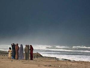 Iranian women look out towards the water on the beach of the Caspian Sea.  (AFP/File) 