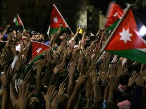 Protesters raise their hands and wave flags near members of the gendarmerie and security forces during a demonstration outside the prime minister's office in the capital Amman late on June 3, 2018. 
Khalil MAZRAAWI / AFP