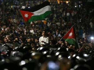 Protesters wave flags near Jordanian security forces during a demonstration outside the prime minister's office in the capital Amman late on June 3, 2018. Khalil Mazraawi /AFP File Photo) 