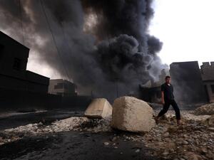 A man walks past an oil well set ablaze by Daesh after the militant group fled Qayyara. (AFP/Safin Hamed)