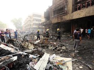 Iraqis, including firefighters, gather at the site of a suicide car bombing claimed by the Islamic State group on July 3, 2016 in Baghdad's central Karrada district. (AFP/Sabah Arar)