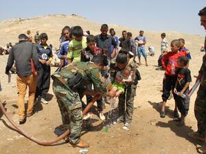 Peshmerga fighters wash the feet of a displaced Iraqi child from the northern village of Hawija as families rest under the protection of Peshmerga forces after fleeing from Daesh on August 17, 2016. (AFP/Marwan Ibrahim)