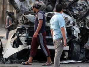 Iraqi men stand next to the wreckage of vehicles in the aftermath of a car bombing at a popular market in Baghdad's northern Shiite district of Sadr City. (AFP/Haidar Mohammed Ali)