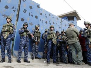 Iraqi policemen gather as they dismantle a security checkpoint on December 20, 2016 in Baghdad following a decision to reduce their number by more than 25 in east of the capital in order to ease traffic. (AFP/Sabah Arar)