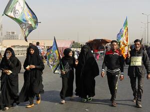 Iraqi security forces stand guard as Shia Muslim pilgrims walk on a road in Baghdad towards the holy city of Karbala a week ahead of the Arbaeen religious festival, the 40th day after Ashura, commemorating the death of Imam Hussein. (AFP/Sabah Arar)