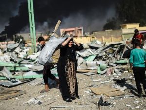 An Iraqi woman and children collect wood and metal at a site, which was targeted by an airstrike a couple of days ago, in Qayyarah region south of Mosul, on October 29, 2016. (AFP/File)