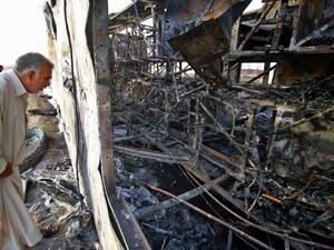 An Iraqi man inspects the wreckage of a bus, that was damaged following a car bomb attack, in the southern Iraqi city of Basra on May 20, 2017. (AFP/Haidar Mohammed Ali)