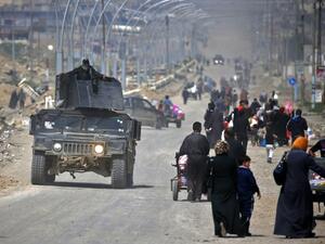 Iraqi security forces drive past civilians fleeing their homes in Mosul's old city on March 30, 2017, due to the ongoing battles between government forces and Daesh fighters. (AFP/Ahmad Gharabli)