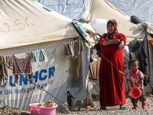 A displaced Iraqi woman and child, who fled the violence in the northern city of Mosul walk by the tents at the Hasan Sham camp on February 11, 2017 east of Erbil. (AFP/Safin Hamid)