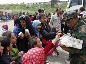 Displaced Iraqis who fled Mosul's Old City receive food as they arrive in the Al-Tayaran neighbourhood on April 8, 2017. (AFP/Ahmad Gharabli)
