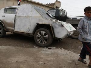 An Iraqi boy walks by a car with defused bomb in a neighborhood recently secured by Iraqi security forces in western Mosul on April 2, 2017, during the retake of the city from Daesh fighters. (AFP/Ahmad Gharabli)