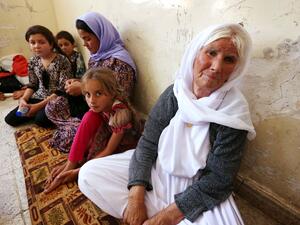 An Iraqi Yazidi family that fled violence in the northern Iraqi town of Sinjar sits at a school. [AFP]