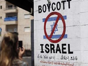 A tourist photographs a sign painted on a wall in the occupied West Bank town of Bethlehem on June 5, 2015, calling to boycott Israeli products. (AFP)