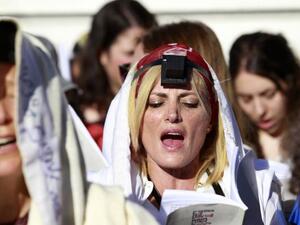 A Jewish female activist (C) from the Women of the Wall prayer rights group wears a prayer shawl and tefillin during a monthly prayer session near the Western Wall plaza in Jerusalem. (Twitter/Jpost)