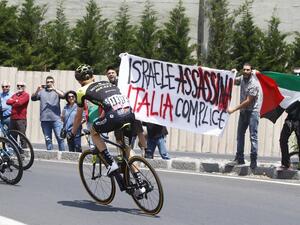 Australia's rider of team Mitchelton-Scott Jack Haig rides past protesters holding a banner reading "Israel assassinate, Italy complicit" before the start of 4th stage between Catania and Caltagirone (Sicily) of the 101st Giro d'Italia, Tour of Italy cycling race, on May 8, 2018 in Catania. (Luk Benies, AFP/File Photo 