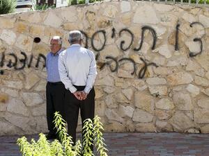 Arab Israeli men stand next to graffiti reading in Hebrew "Arabs Out" on the wall of a mosque in the northern Israeli city of Umm al-Faham on April 18, 2014. (AFP/ File Photo)