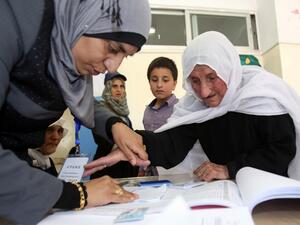 An elderly Jordanian woman is assisted by a member of the electoral commission as she votes in the parliamentary elections at a polling station in the capital Amman on September 20, 2016. (AFP/Khalil Mazraawi)