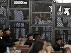 Journalists stand in the defendants' cage in a 2014 trial in Egypt. (AFP/File) Journalists stand in the defendants' cage in a 2014 trial in Egypt. (AFP/File)