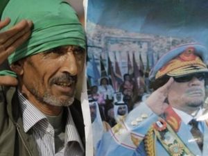 احد انصار القذافي يحمل لوحة له في الزي العسكري