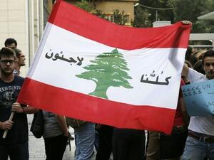 Lebanese protesters hold a Lebanese national flag on which is written in Arabic, "We are all refugees" on July 18, 2016 in the capital Beirut. (AFP/Joseph Eid)