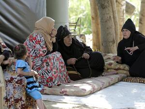 Syrian refugee women sit on mats talking at an unofficial camp for refugees in the village of Bar Elias in the Bekaa Valley in central Lebanon (AFP/ JOSEPH EID)