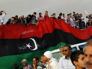 Libyans hold a large version of their national flag during a demonstration. (AFP Photo / Abdullah Doma)