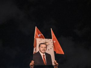 A supporter of Justice and development party (AKP) holds a banner picturing Turkish president Recep Tayyip Erdogan during a rally near the headquarters of the conservative AKP party on March 31, 2019. (AFP)