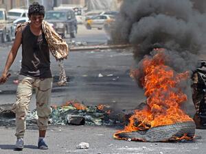 A Yemeni man walks past burning tires in Aden on Sept. 6. (Saleh al-Obeidi/AFP) 