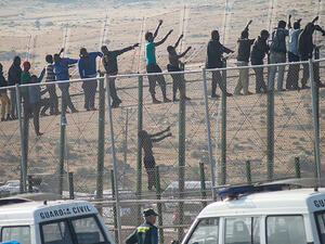 Would-be immigrants stand atop a border fence separating Morocco from the Spanish enclave of Melilla on May 1, 2014, following a morning assault on the border in an attempt to cross into Spain. (AFP/File) Would-be immigrants stand atop a border fence separating Morocco from the Spanish enclave of Melilla on May 1, 2014, following a morning assault on the border in an attempt to cross into Spain. (AFP/File)