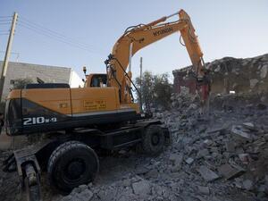 Rafet Dabash (not pictured), a Palestinian from the east Jerusalem district of Sur Baher, has his house destroyed by a bulldozer. (AFP PHOTO / AHMAD GHARABLI)