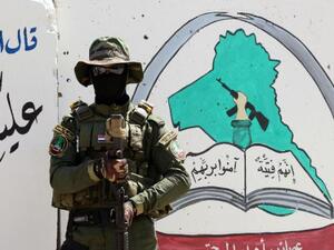 An Iraqi fighter of the Shia militia Asaib Ahl al-Haq (The League of the Righteous) stands guard outside the militia's headquarters in Basra, on May 18, 2015. (AFP/Haidar Mohammed Ali)