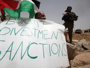 A Palestinian holds a placard as part of a protest during which they try to set up a tent on 8 June, 2013 near the Jewish settlement of Bat Ayin and the West Bank village of Surif, west of Hebron. (AFP/File)