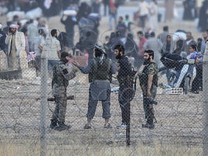 Men, believed to be Daesh militants, speak as people carry belongings back to Tal Abyad. (AFP/File)