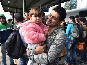 A Syrian man holds his child as he gets off the train in Munich, Germany. (AFP/File)