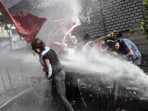 Protesters try to protect themselves as Turkish anti-riot police fire water cannon to disperse crowd. (AFP/File)